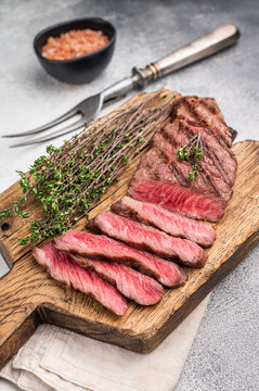 Flavorsome beef Denver shoulder tender, grilled in BBQ to juicy perfection, served with fresh herbs. grey background. top view