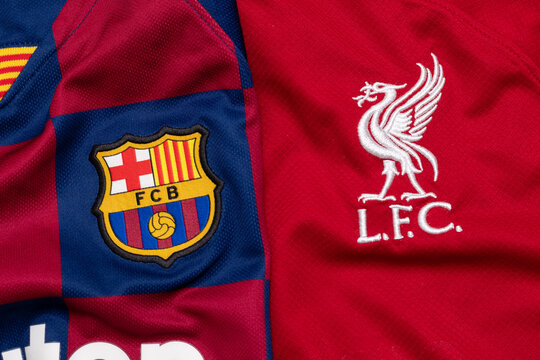 KYIV, Ukraine, January 9. Close-up of FC Barcelona and Liverpool FC jerseys side by side. Detailed club emblems on red and blue-red checkered fabric, sports rivalry concept.