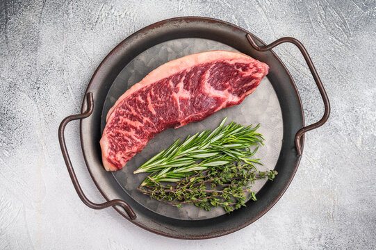 Raw rump cap steak, beef meat, showcasing its rich color and marbling.  grey background. top view