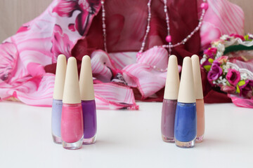 Set of nail polishes on a white table, against pinkish fabric. Ideal for manicure and pedicure promotions, nail design tutorial and beauty spa content.