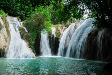 Fototapeta premium Thluvalley Waterfall in Pacitan, East Java, Indonesia. This photo captures the serenity and coolness of pristine nature, with the waterfall cascading swiftly amidst the greenery.
