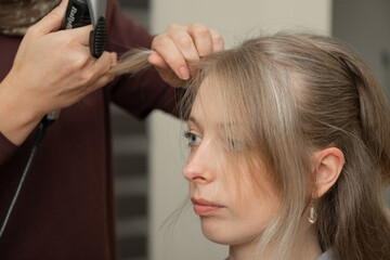 Fototapeta premium Hairdresser Curling Hair of Woman Using Styling Iron