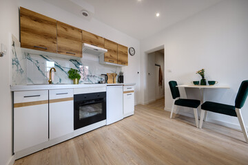 Kuchnia w apartamencie w jasnych kolorach , biel, brązowe fronty szafek