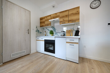 Kuchnia w apartamencie w jasnych kolorach , biel, brązowe fronty szafek