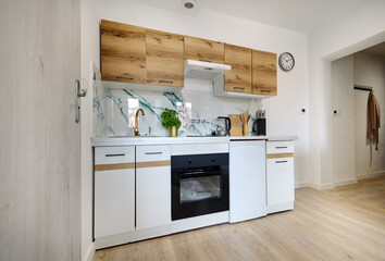 Kuchnia w apartamencie w jasnych kolorach , biel, brązowe fronty szafek