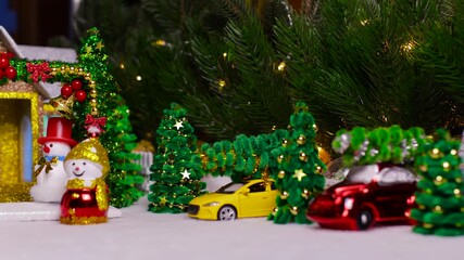 A Christmas village with colorful cars among Christmas trees, snowmen, and a house with a decorated arch in the foreground