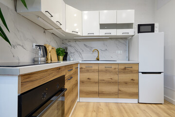 Kuchnia w apartamencie w jasnych kolorach , biel, brązowe fronty szafek, stolik śniadaniowy