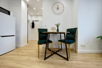 Kuchnia w apartamencie w jasnych kolorach , biel, brązowe fronty szafek, stolik śniadaniowy