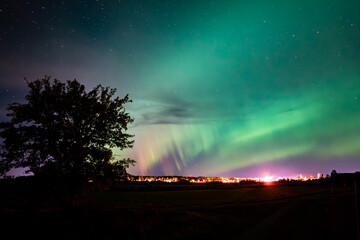 Northern lights dancing over country road in north of Sweden