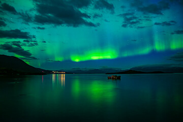 Northern lights dancing over calm lake in Abisko national park in north of Sweden