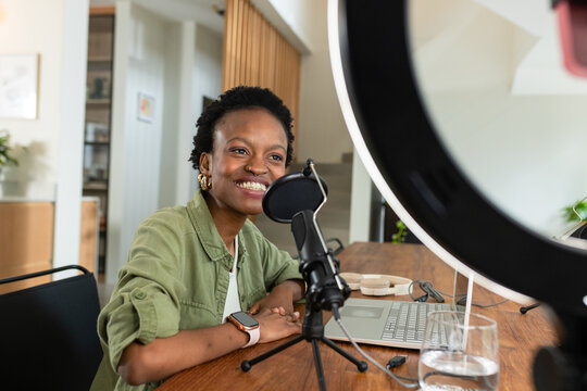 African American woman recording podcast at home office using microphone pop filter and ring light