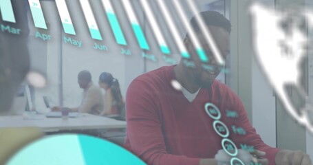 Working man in red sweater tapping laptop at modern office, with holographic charts and coffee cup