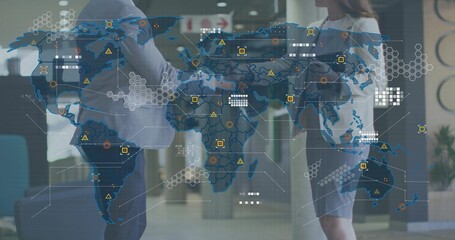 Talking colleagues wearing business attire, holding phone and tablet in lobby with holographic map