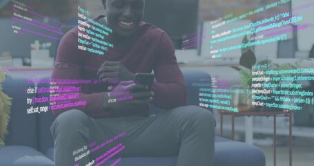 Holding smartphone smiling man viewing code overlays on sofa wearing maroon shirt and gray pants
