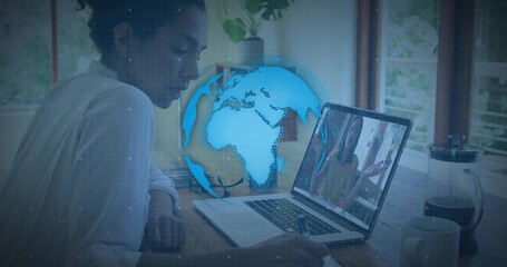 Writing woman in light blouse taking notes at home desk, using laptop with blue globe overlay