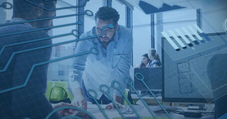 Pointing man in button-up shirt leaning over desk at office showing plans, monitors and safety vest © vectorfusionart