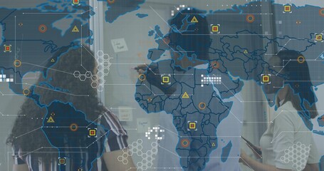 Pointing woman wearing dark blazer leading team at glass wall, with notes, tablet and map overlays