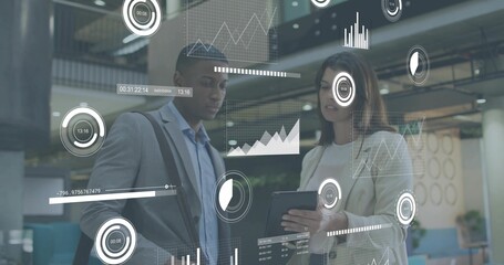Reviewing tablet, two colleagues in light blazers with shoulder bag in atrium, showing AR analytics