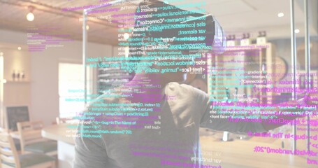 Standing adult male wearing gray hoodie, using AR headset at modern cafe, viewing floating code