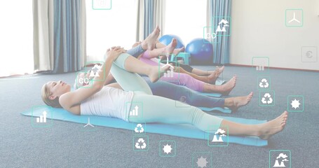 Stretching four adults hugging knees in carpeted exercise studio, white tank, blue stability balls