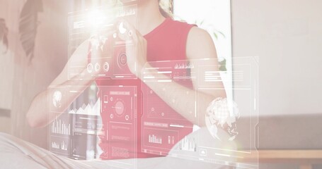 Interacting woman in sleeveless red top using holographic UI panels at home lounge, data charts