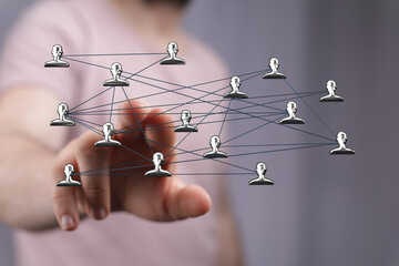 Hand reaching towards a network of connected user icons, illustrating a concept of connectivity, relationships, teamwork, and digital interactio