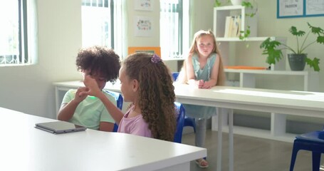 Diverse youths in green, pink T-shirts glancing at tablet, playing hand game and tapping in class