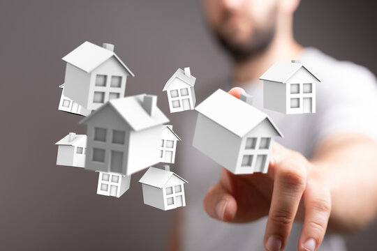Person touching small houses symbolizing real estate, investments, home ownership, and property.  Focus on business, growth, and the future of h