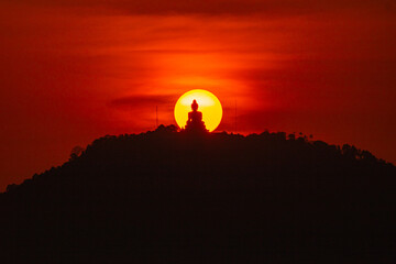 he sun is circling behind the Buddha on the mountain as he meditates. The clouds float lazily in...