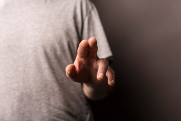 Close up of a man's hand extending forward. It's a gesture of touch or click, set on a dark...