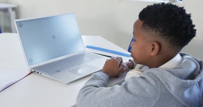 Student is following registration marks on laptop, pointing and counting fingers at desk
