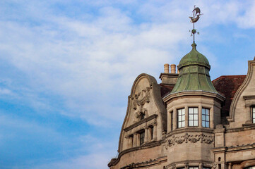 The building's architecture is a striking example of highly decorative Victorian style, reminiscent of the Tudor Revival style. The facade is made of weathered stone, adding to its historic character.