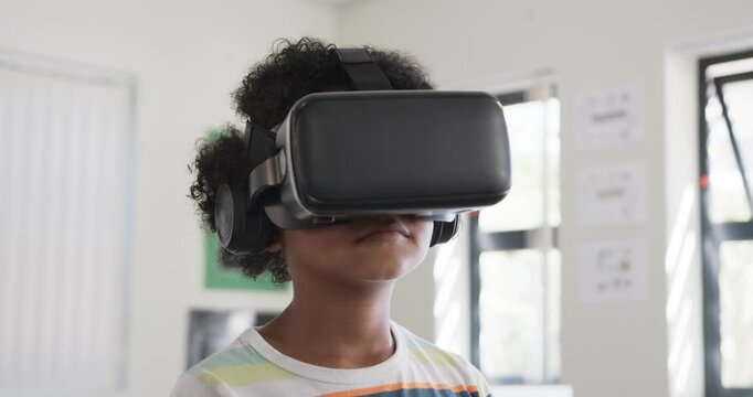 After pause child in black VR headset is tilting, pinching and moving virtual objects in classroom