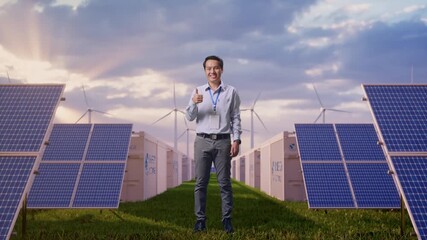 Full Body Shot Captures Of An Asian Male Worker Standing at Energy Farm Solar Panels, Battery Storage and Wind Turbines, His Broad Smile At The Camera And Giving Thumbs Up