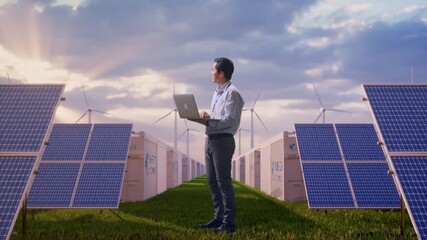 Full Body Side View Of An Asian Male Worker at Energy Farm Solar Panels, Battery Storage and Wind Turbines, Observes By Looking Up Before He Come To Concentrating On The Laptop And Keep On Typing