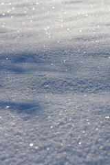 Vertical close-up of sparkling white snow texture in bright sun