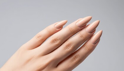 Close up of a perfectly manicured woman's hand displaying elegant long pointed beige nude nails