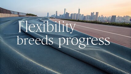 Futuristic adaptive textile material with urban cityscape and motivational text 'flexibility needs progress'