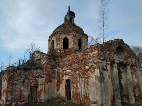abandoned architecture, a damaged dome tops a faded brick building, surrounded by overgrown foliage, hinting at a historic or religious past
