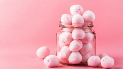 Glass jar filled with fluffy pink cotton candy balls on a vibrant pastel pink background