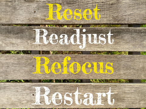 Reset Readjust Refocus Restart Motivation Quote on Wooden Background