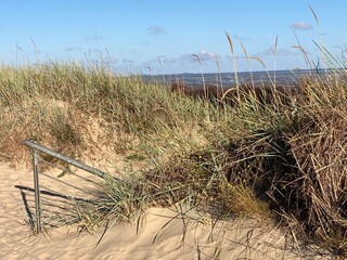 Blick &uuml;ber den Deich mit Treppe und Gr&auml;sern am Strand der Nordsee in Cuxhaven 