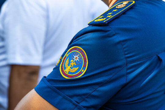 Close-up of the official sleeve patch of the Ministry of Emergency Situations (MES) of the Kyrgyz Republic on a dark blue uniform fabric, symbol of disaster response and civil protection in Bishkek