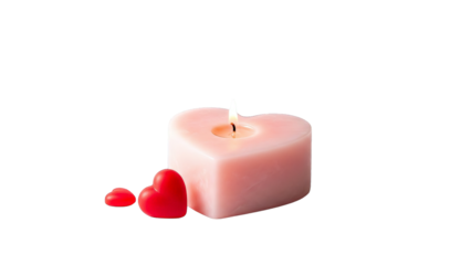 A lit heart shaped candle glows softly next to two small red hearts on a white surface.