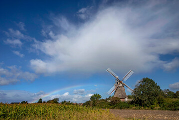 Oldsumer Windm&uuml;hle mit Regenbogen, Wolkenhimmel und Maisfeld im Vordergrund auf der Nordseeinsel F&ouml;hr