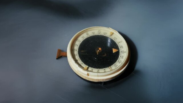 Vintage navigational compass with a broken piece sits on a dark surface. Thick white smoke billows and swirls around the object, creating a mysterious atmosphere.