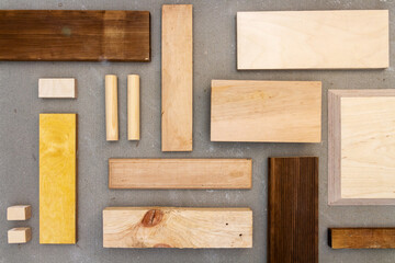 Flat lay of various wood and plywood pieces on concrete texture. Carpentry background.