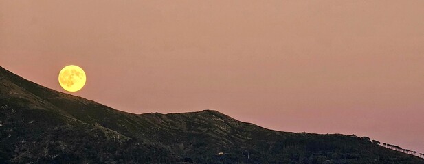 Genova, Italy - January 3, 2026: An amazing photography of the full moon over the city of Genova by...