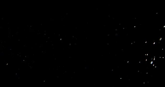 Tiny dust randomly flying in the smoky air, empty space template for objects advertisement. Many dust particles of white powder in low light on empty dark black contrast background, close shot.