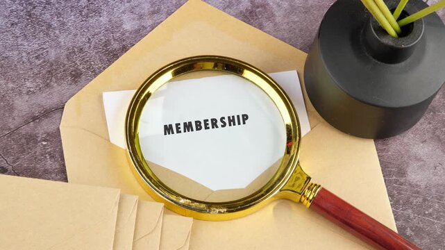 A word gradually becomes legible on a piece of paper under a magnifying glass. The word evolves from M with question marks to finally reveal MEMBERSHIP